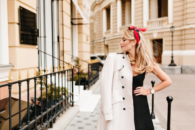 Free photo beautiful slim woman in black dress posing with pleasure on the old narrow street