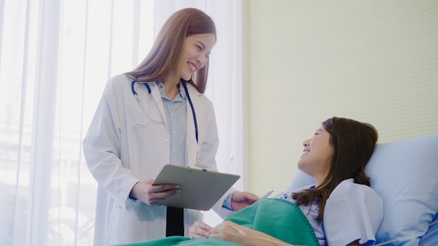 Free Photo beautiful smart asian doctor and patient discussing and explaining something with clipboard 