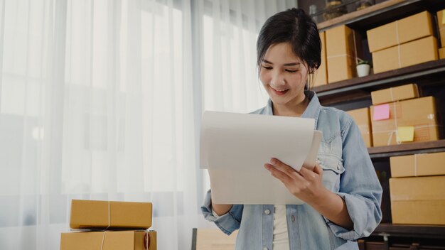 Beautiful smart Asian young entrepreneur business woman owner of SME checking product on stock 