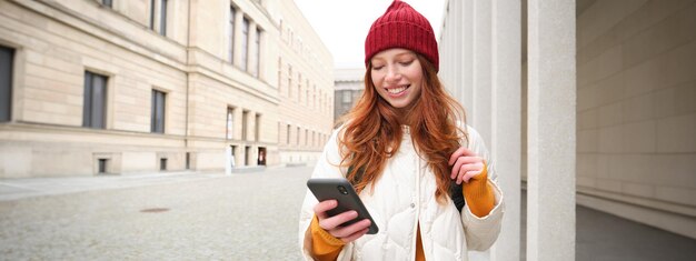 Free Photo beautiful smiling girl tourist with backpack holding smartphone using map on mobile phone