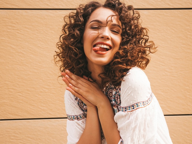 Beautiful smiling model with afro curls hairstyle dressed in summer hipster white dress.