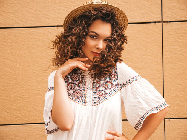 Beautiful smiling model with afro curls hairstyle dressed in summer hipster white dress.