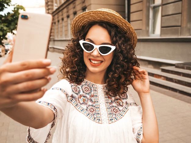 Beautiful smiling model with afro curls hairstyle dressed in summer hipster white dress.