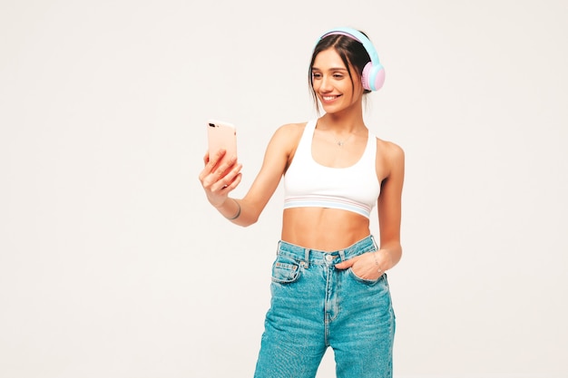 Beautiful smiling woman dressed in jeans clothes. carefree model listening music in wireless headphones