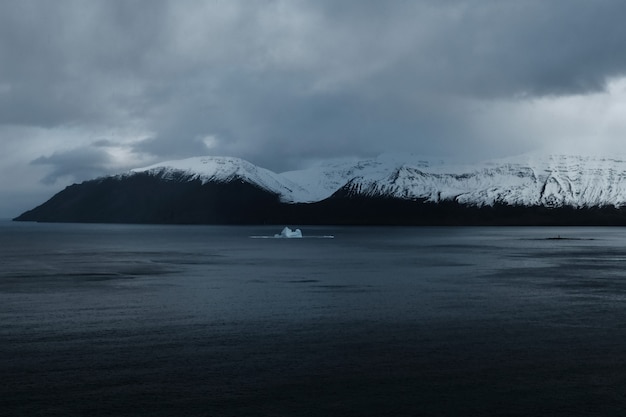 Beautiful snowy mountains with a lake and dark cloudy sky