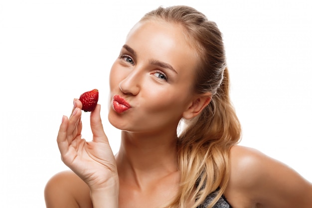 Beautiful sportive woman posing, eating strawberry 