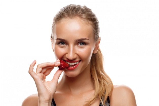 Beautiful sportive woman posing, eating strawberry 