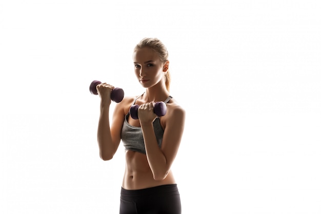 Beautiful sportive woman training with dumbbells 