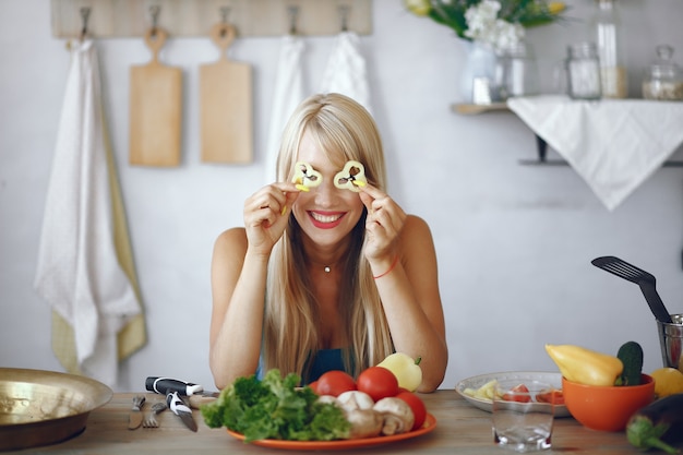 Free photo beautiful and sporty girl in a kitchen with a vegetables