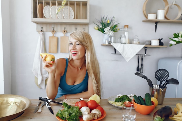 Free photo beautiful and sporty girl in a kitchen with a vegetables