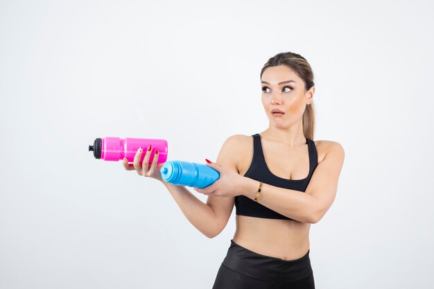 Beautiful sporty woman holding bottles with water on white