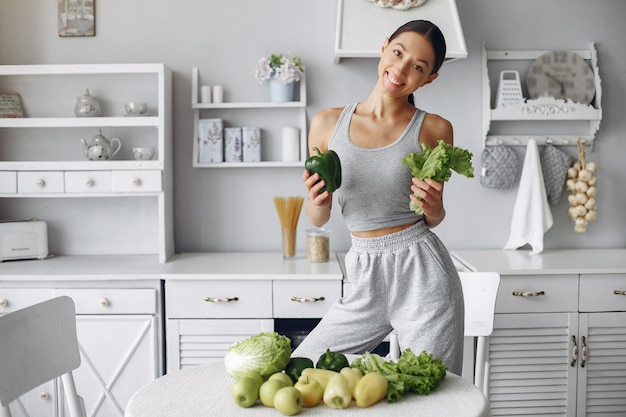 Free photo beautiful and sporty woman in a kitchen with vegetables