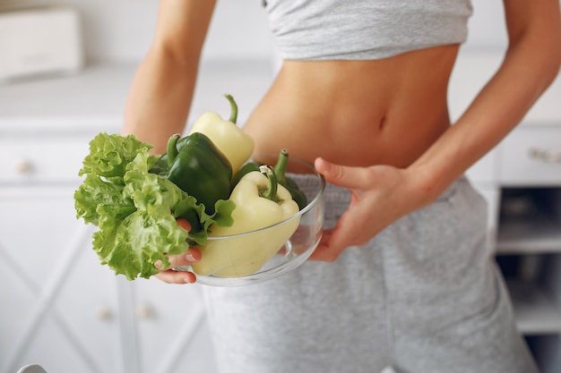 Beautiful and sporty woman in a kitchen with vegetables