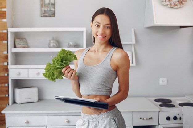 Beautiful and sporty woman in a kitchen with vegetables