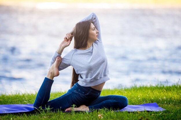 Beautiful sporty young woman working out on riverbank