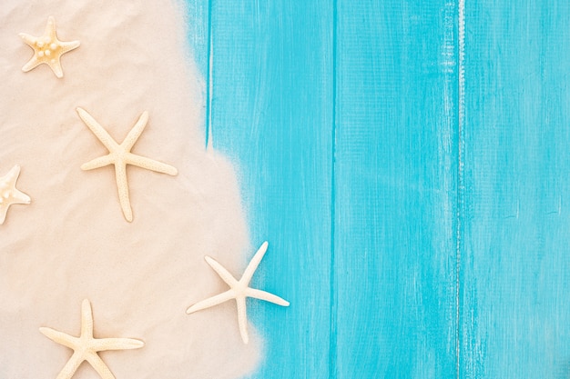 Beautiful starfishes with sand on wooden blue background