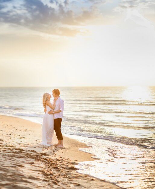 Beautiful stylish couple posing in sunlight on the beach