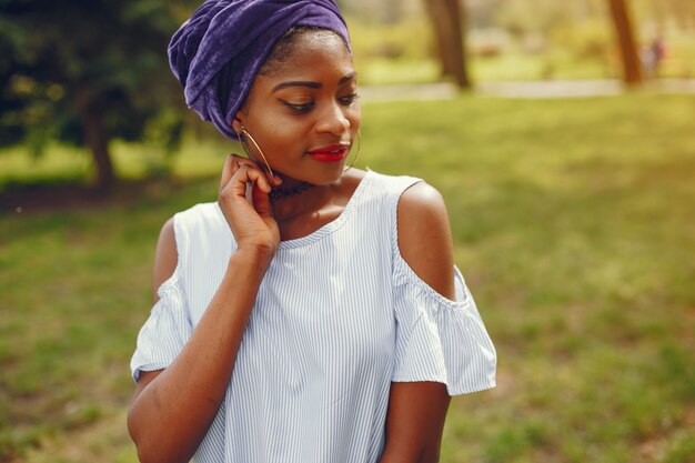 A beautiful and stylish dark-skinned girl walks in a sunny summer city