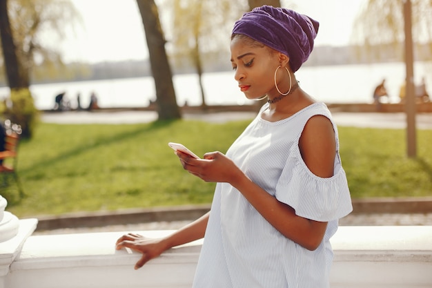 A beautiful and stylish dark-skinned girl walks in a sunny summer city