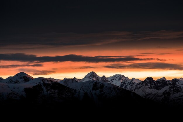 Beautiful sunrise on the horizon with tall mountains and snowy hills and amazing dark sky