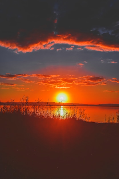 Beautiful sunset at the lake with greenery on the coast and amazing cloudy sky