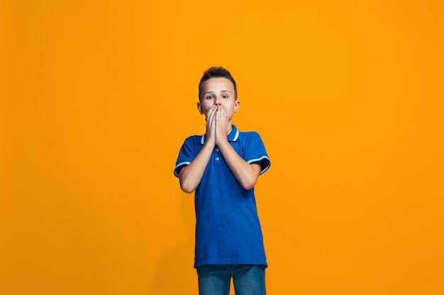 Beautiful teen boy looking suprised isolated on orange