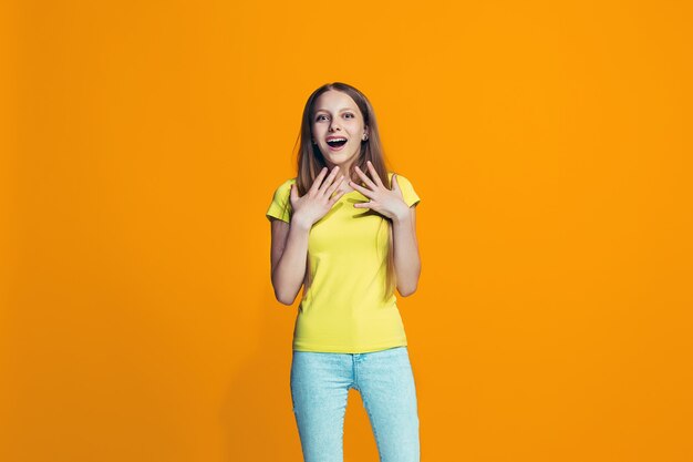 Beautiful teen girl looking suprised isolated on orange