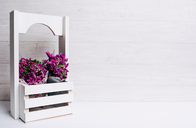 Free Photo beautiful tiny purple flowers in crates on desk against wooden backdrop