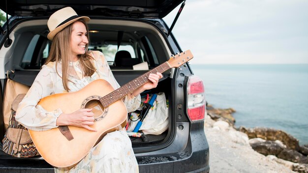 Beautiful traveller playing guitar on vacation