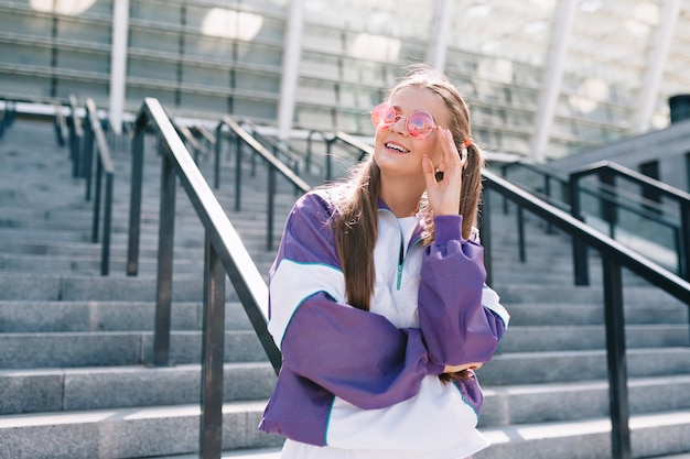 Free Photo beautiful trendy young woman in stylish clothes wearing pink sunglasses and smiling