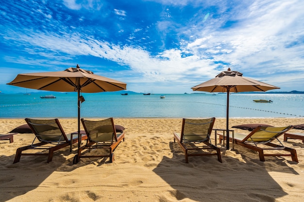 Beautiful tropical beach sea and ocean with coconut palm tree  and umbrella and chair on blue sky 