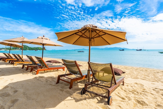 Beautiful tropical beach sea and ocean with coconut palm tree  and umbrella and chair on blue sky 