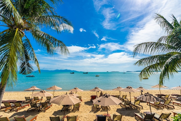 Beautiful tropical beach sea and ocean with coconut palm tree  and umbrella and chair on blue sky 