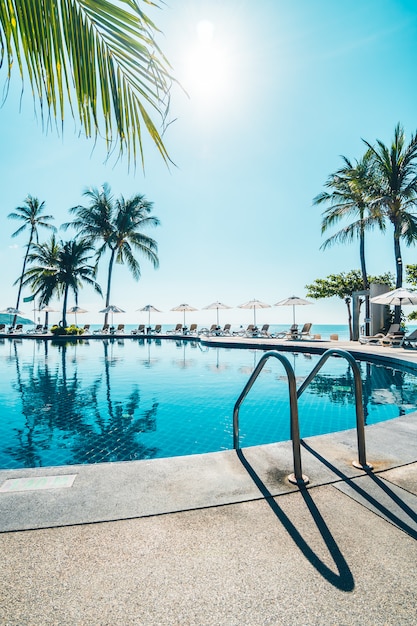 Free photo beautiful tropical beach and sea with umbrella and chair around swimming pool