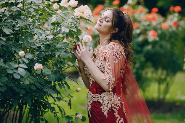 A beautiful Turkish girl in a long red dress walks in the summer old city