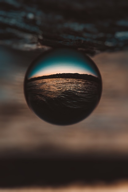 Beautiful vertical closeup shot of a glass ball with the reflection of the breathtaking sunset