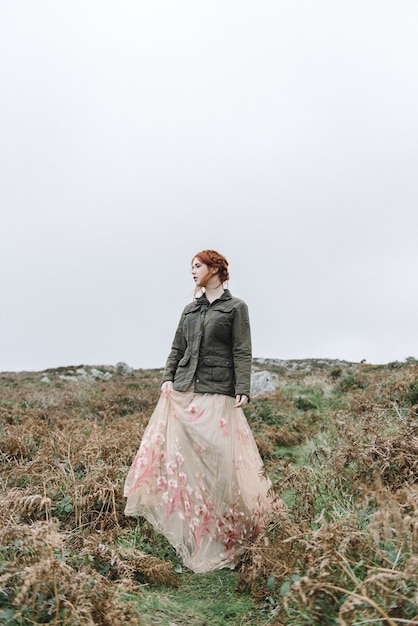 Beautiful vertical picture of a ginger female with a pure white skin in an attractive light gown