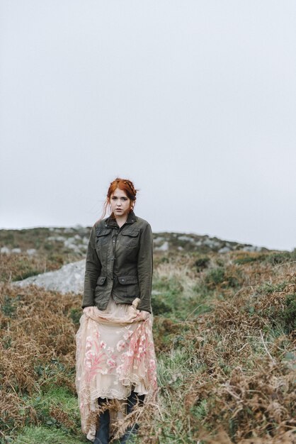 Beautiful vertical picture of a ginger female with a pure white skin in an attractive light gown