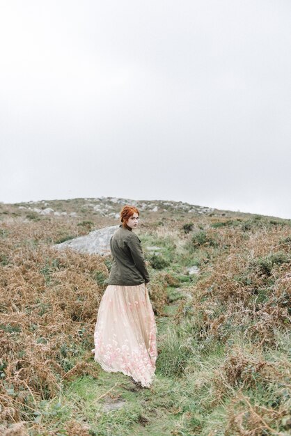 Beautiful vertical picture of a ginger female with a pure white skin in an attractive light gown