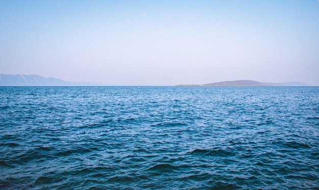 Beautiful view of a blue sea with mountains on the background under a clear sky