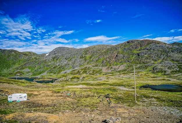 Beautiful view of the grass-covered mountains and fields under the clear blue sky in Sweden