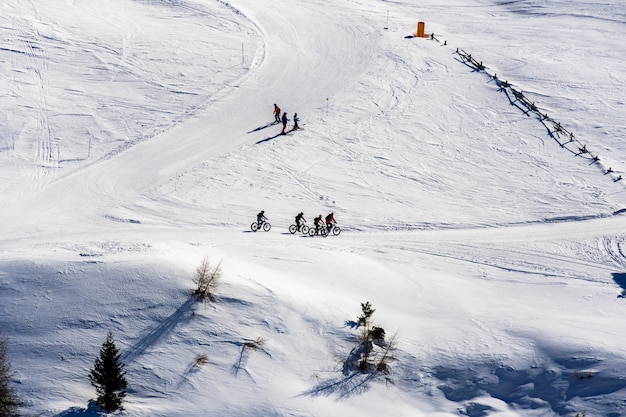 Free Photo beautiful view of people cycling and skiing across snowy mountains in south tyrol, dolomites, italy