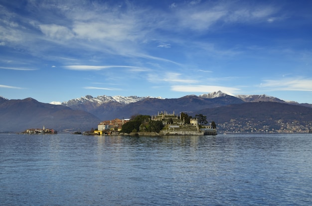 Beautiful view of a small island in the middle of the sea near the mountains under the blue sky