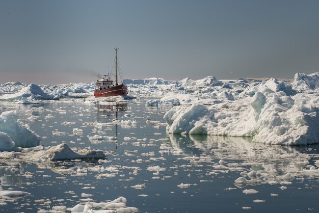 Beautiful view of tourist boat sailing through icebergs in Disko Bay, Greenland