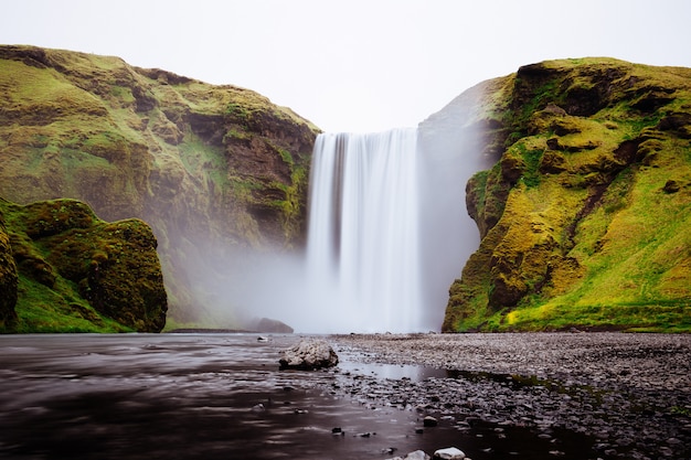 Beautiful waterfall between green hills in Skogafoss, Iceland