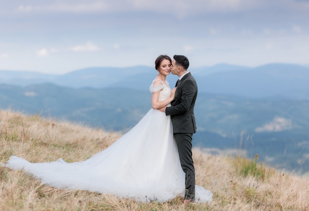 Beautiful wedding couple is kissing on the top of a mountain in the autumn warm day