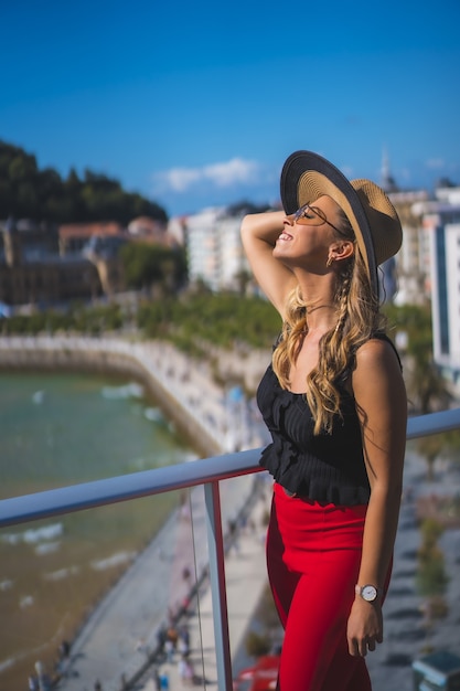 Beautiful white Caucasian woman happily standing on the balcony of the hotel room with a sea view