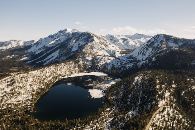 Free Photo beautiful wide shot of mountains covered with snow surrounded by trees and a lake