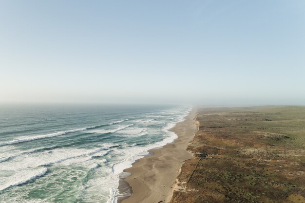 Beautiful wide shot of ocean near a desert under a clear blue sky