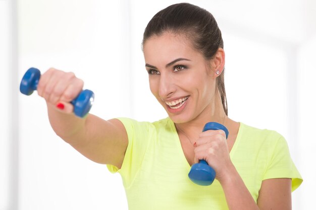 Beautiful woman attack holding in her arms dumbbells